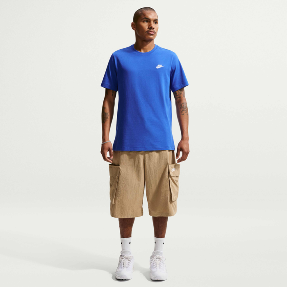 Man wearing a blue Nike t-shirt and beige cargo shorts on a white background