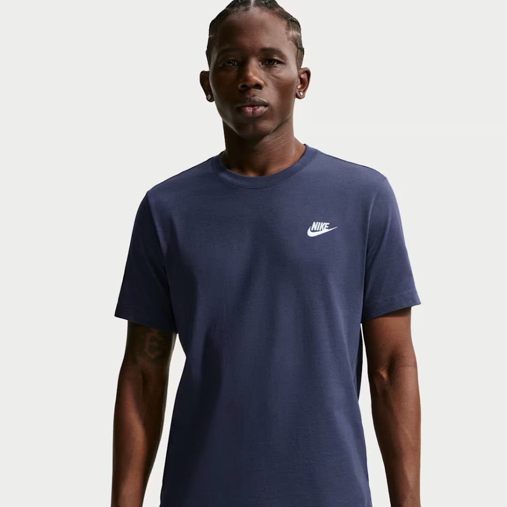 Man wearing a navy blue t-shirt with a white logo on a light gray background