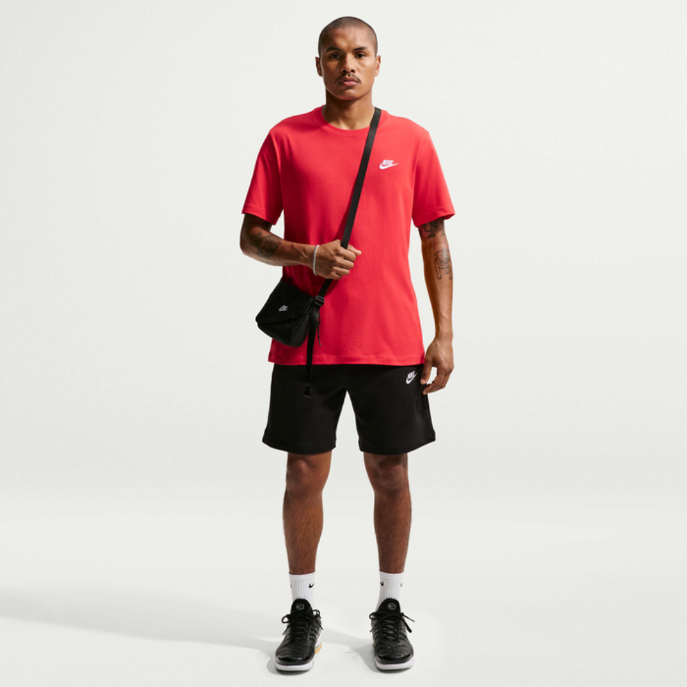 Man wearing a red t-shirt and black shorts with a white background