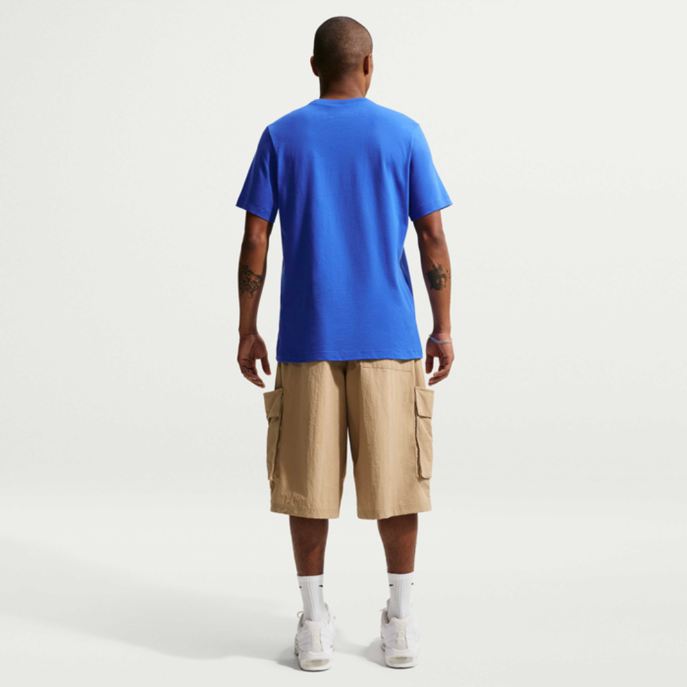 Man wearing a blue t-shirt and beige cargo shorts on a white background