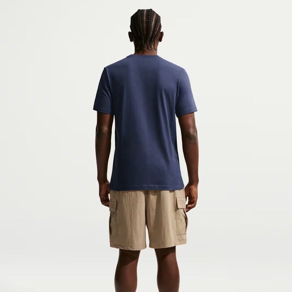 Person wearing a navy blue t-shirt and beige shorts on a white background