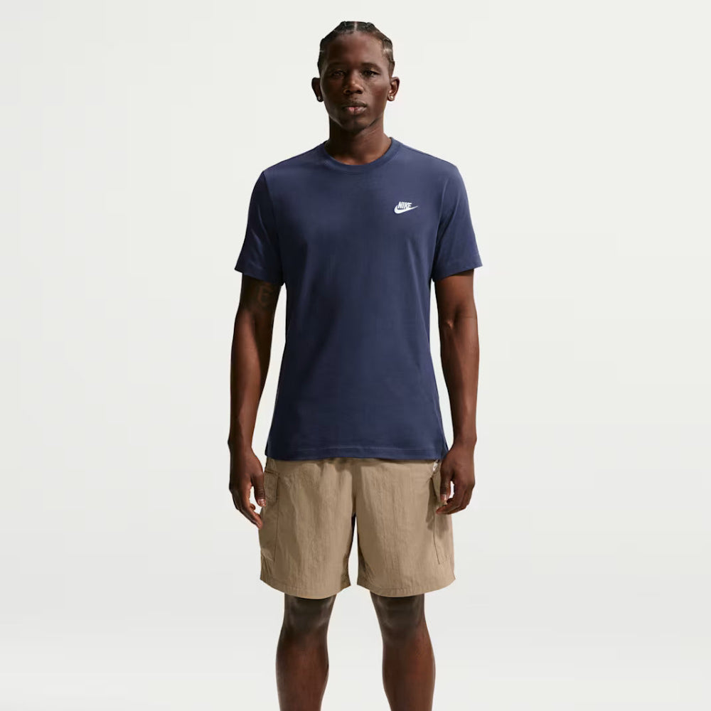 Person wearing a navy blue t-shirt with a Nike logo, beige shorts, and white sneakers on a white background